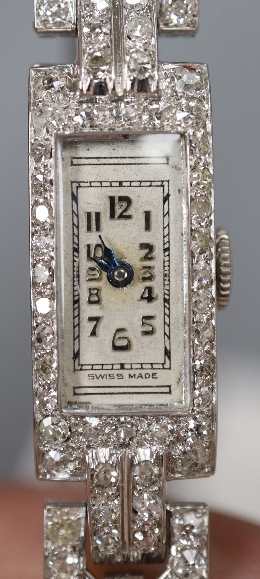 A ladys white metal (stamped platinum) and diamond set cocktail watch, on twin leather strap with steel clasp, approx 18cm,